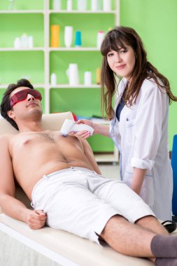 Genç adam epilasyon için doktoru ziyaret ediyor.