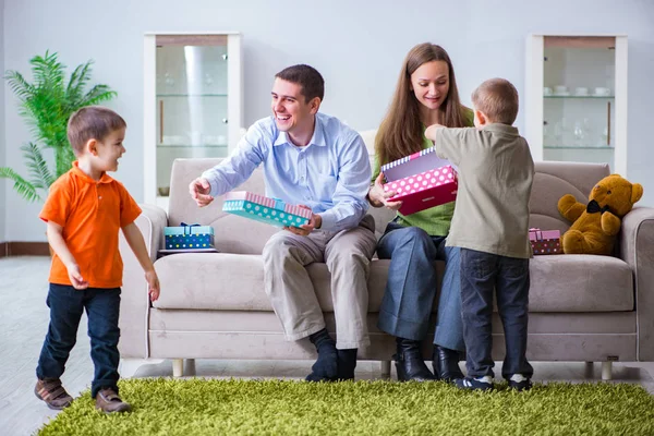 Padres jóvenes repartiendo regalos de Navidad en casa — Foto de Stock