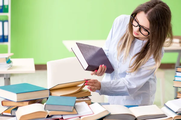 Ung kvinnlig student förbereder sig för tentor med många böcker — Stockfoto