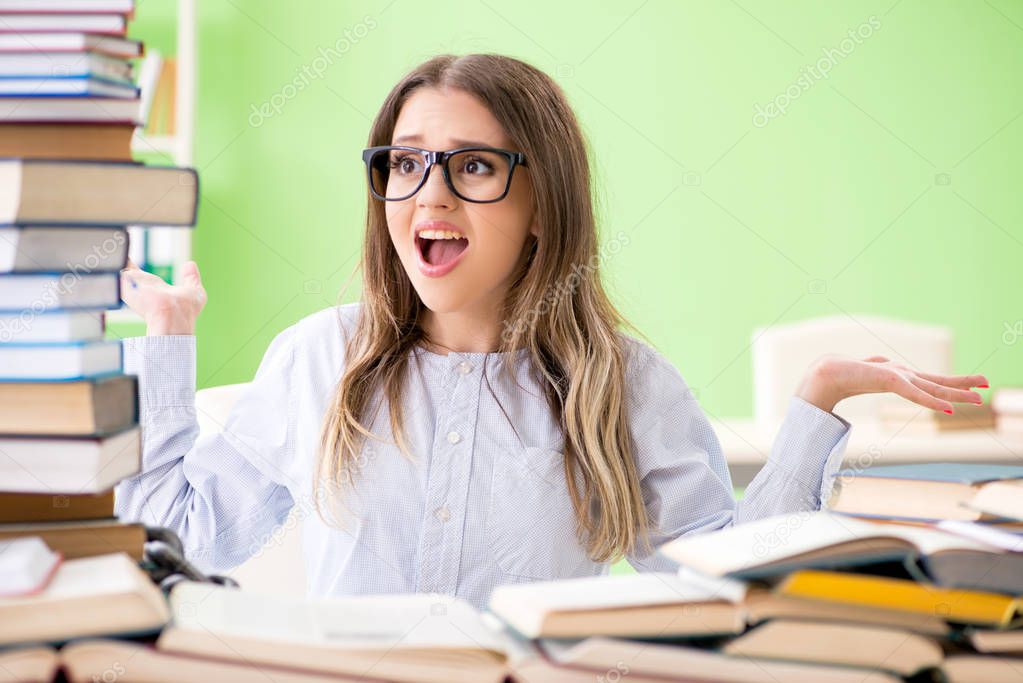 Young female student preparing for exams with many books 