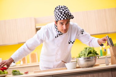 Genç profesyonel aşçı evde salata hazırlıyor.