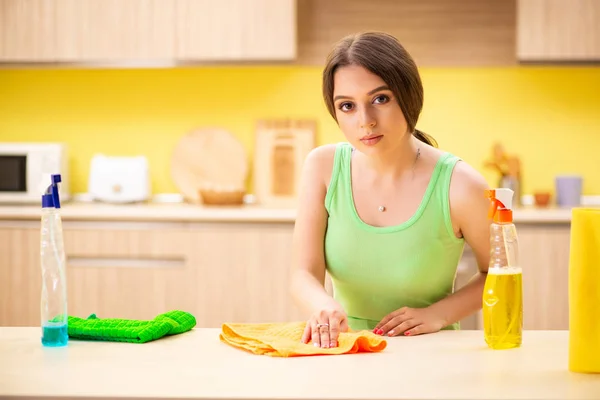 Jonge mooie vrouw polijsten tafel in de keuken — Stockfoto