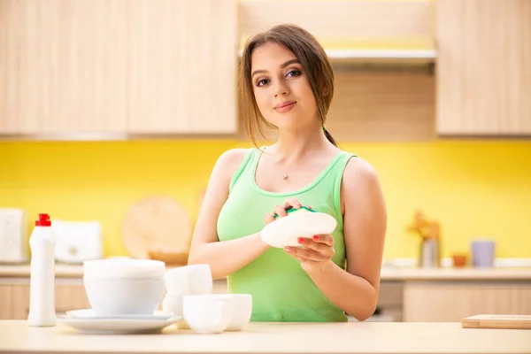 Młoda kobieta sprzątanie i mycie naczyń w kuchni — Zdjęcie stockowe