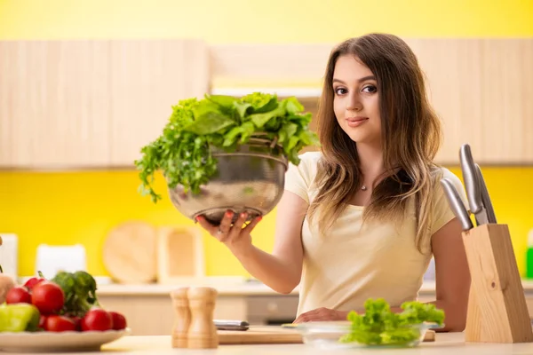 Νεαρή γυναίκα ετοιμάζει σαλάτα στο σπίτι στην κουζίνα — Φωτογραφία Αρχείου