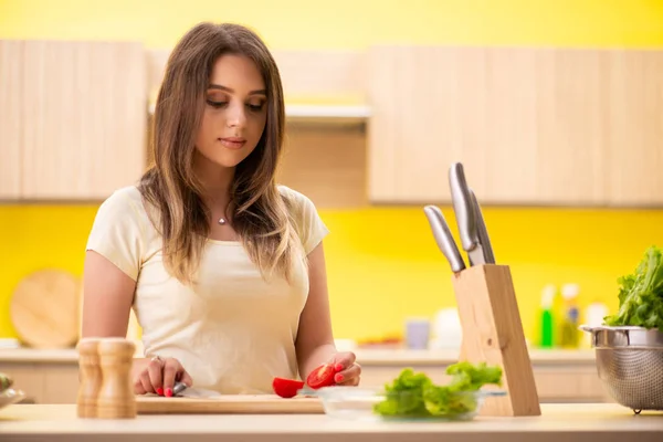 Mujer joven preparando ensalada en casa en la cocina — Foto de Stock