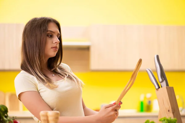 Mujer joven preparando ensalada en casa en la cocina — Foto de Stock