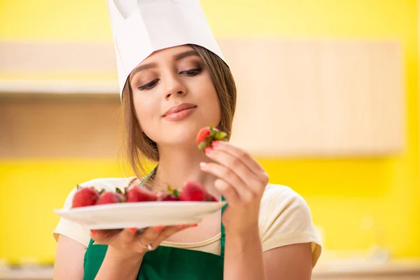 Jovem cozinheira comendo morangos — Fotografia de Stock