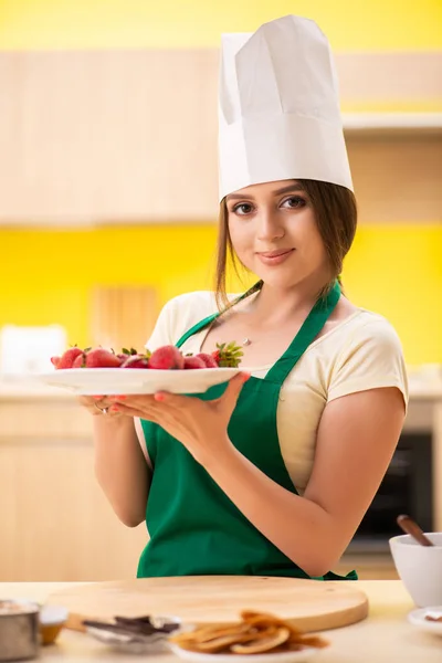 Jovem cozinheira comendo morangos — Fotografia de Stock