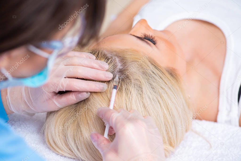 Plastic surgeon preparing for operation on woman hair 