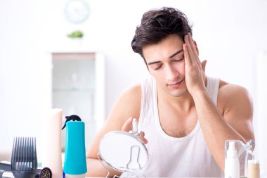 Genç yakışıklı adam aynaya bakıyor. 