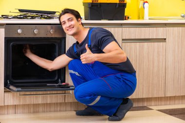 Genç müteahhit mutfak mobilyalarını monte ediyor.