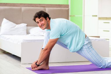 Pijamalı genç adam sabah egzersizi yapıyor. 