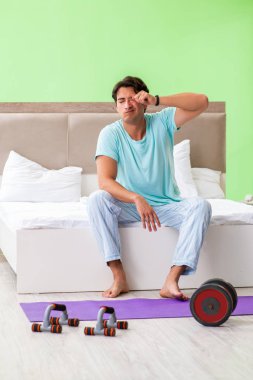 Pijamalı genç adam sabah egzersizi yapıyor. 