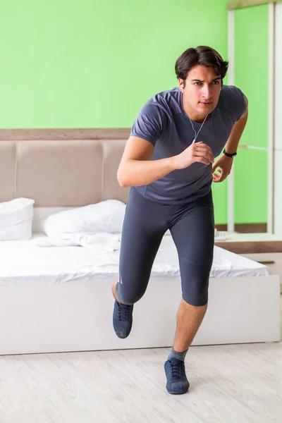 Joven hombre guapo haciendo ejercicios matutinos en la habitación del hotel —  Fotos de Stock