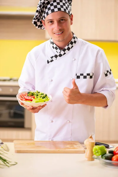 Jovem cozinheiro profissional preparando salada na cozinha — Fotografia de Stock