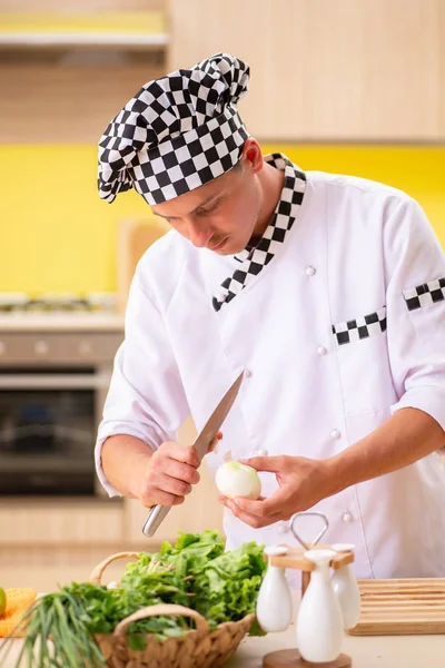 Joven cocinero profesional preparando ensalada en la cocina — Foto de Stock