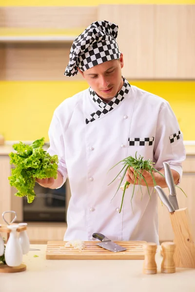 Joven cocinero profesional preparando ensalada en la cocina — Foto de Stock