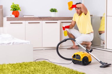 Genç yakışıklı adam yatak odasını temizliyor.