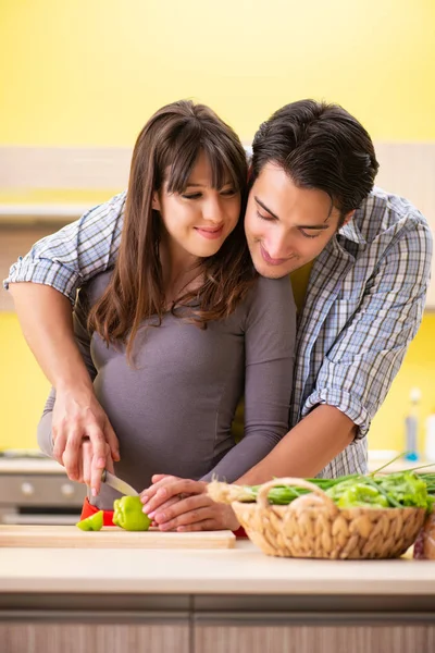 Man en zwangere vrouw het bereiden van salade in keuken — Stockfoto