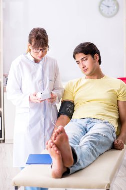 Genç doktor hastaların tansiyonunu ölçüyor.