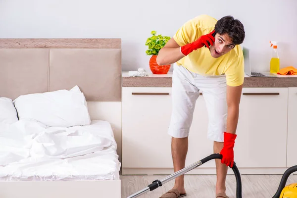 Giovane uomo bello pulizia in camera da letto — Foto Stock