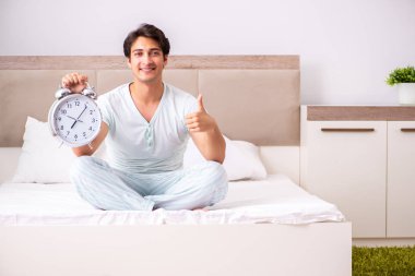 Genç adam yatak odasında yoga yapıyor.