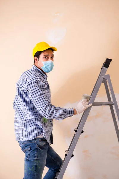 Contratista joven lijando pared con papel de lija — Foto de Stock