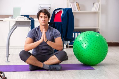 Ofiste egzersiz yapan genç bir erkek.