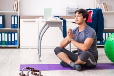 Ofiste egzersiz yapan genç bir erkek.