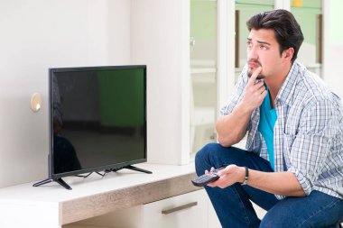 Genç adam evde televizyon tamir ediyor. 