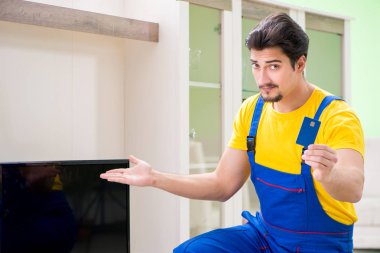 Erkek profesyonel tamirci evde televizyon tamir ediyor.