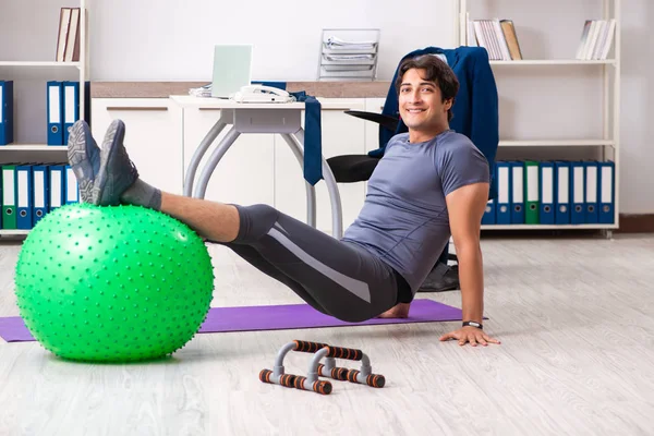 Young male employee exercising in the office — Stock Photo, Image