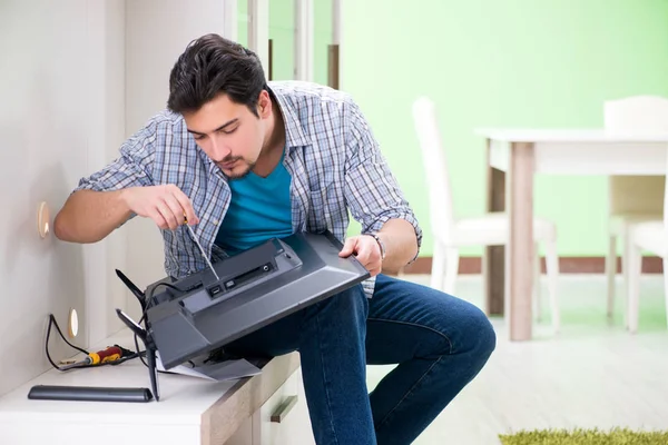 Jovem marido reparar tv em casa — Fotografia de Stock