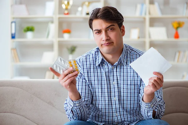 Young man sitting on the sofa with pills and prescription — Stock Photo, Image