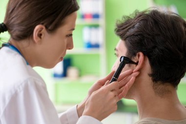 Tıbbi muayene sırasında kadın doktor hastaların kulaklarını kontrol ediyor. 