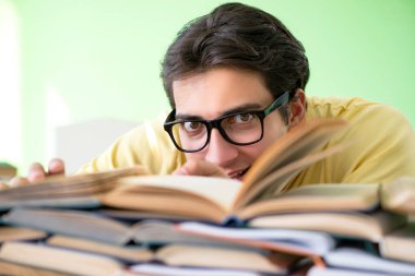 Sınavdan önce okumak için çok fazla kitabı olan öğrenci