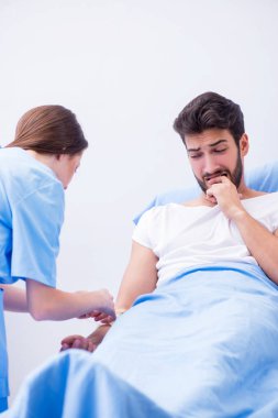 Kadın doktor erkek hastayı hastanede muayene ediyor.