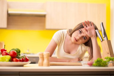 Genç bayan mutfakta salata hazırlıyor.