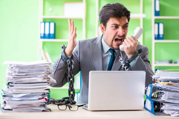 Empregado acorrentado à sua mesa devido à carga de trabalho — Fotografia de Stock