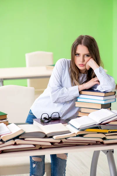 Jovem estudante se preparando para exames com muitos livros — Fotografia de Stock