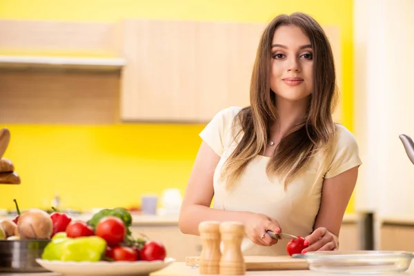 Jovem mulher preparando salada em casa na cozinha — Fotografia de Stock