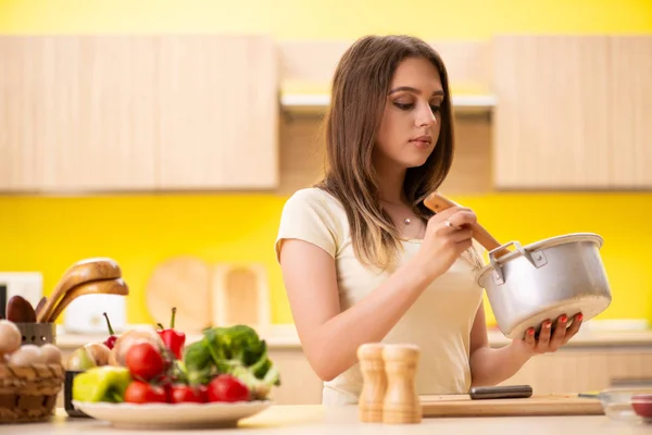 Νεαρή γυναίκα μαγειρεύει σούπα στην κουζίνα στο σπίτι — Φωτογραφία Αρχείου