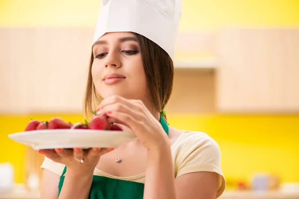 Jovem cozinheira comendo morangos — Fotografia de Stock
