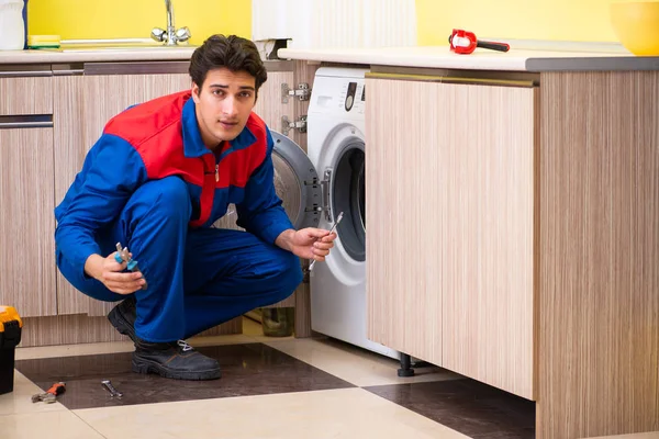 Reparador reparando lavadora en la cocina — Foto de Stock