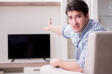 Genç adam evde televizyon izliyor.