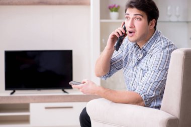 Genç adam evde televizyon izliyor.