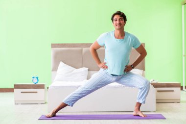 Pijamalı genç adam sabah egzersizi yapıyor. 