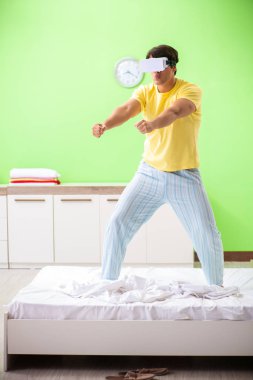 Yatak odasında sanal gözlüklü genç adam. 