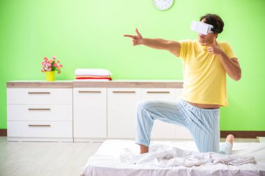 Yatak odasında sanal gözlüklü genç adam. 