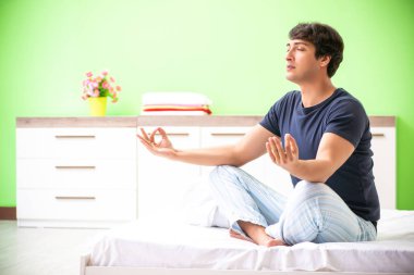 Pijamalı genç adam sabah egzersizi yapıyor. 